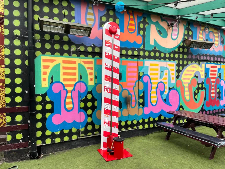 Red and white high striker set up in a beer garden